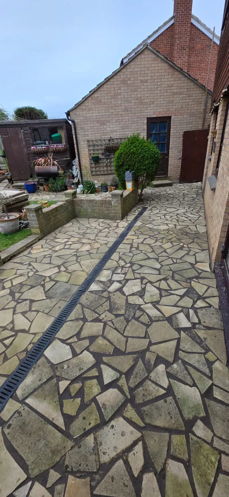 Natural stone crazy paving patio with integrated drainage channel in a residential garden