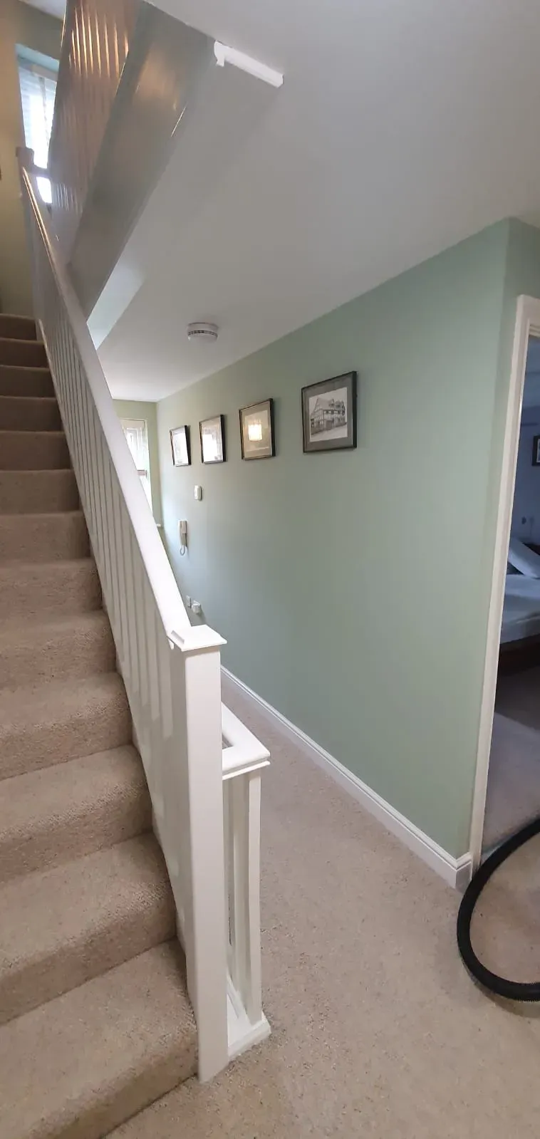 Interior painting and decorating of a hallway and staircase with sage green walls and white trim in a Suffolk home.