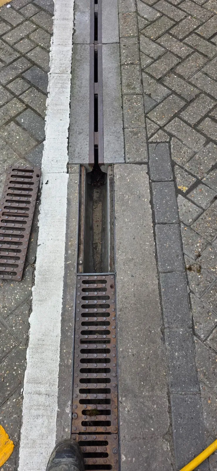 Close up of a channel drain repair and inspection in a block-paved driveway in Felixstowe.